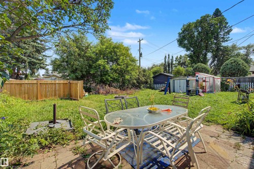 Expansive backyard featuring a patio area with paver stones, a wood privacy fence, and a diverse assortment of mature trees and shrubbery - 8215 149 Street Nw, Edmonton, AB - Outdoor With Backyard