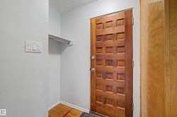 Solid wood entry door with square panel design, wood-finish flooring, and integrated coat closet with shelf and hanging rod - 