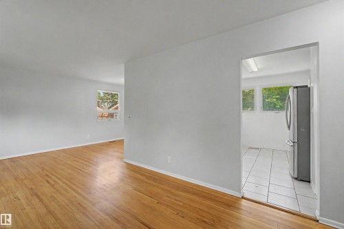 Bright room featuring wood-finish flooring, white walls, and a window - 8215 149 Street Nw, Edmonton, AB - Indoor Photo Showing Other Room