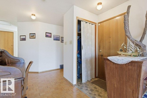 Entryway featuring wood-finish flooring, a light wood door, a bi-fold closet door, and ceiling-mounted light fixtures - 10459 66 Avenue Nw, Edmonton, AB - Indoor