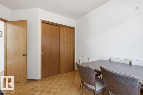 Hardwood parquet flooring with a built-in closet featuring wood-finish sliding doors - 10459 66 Avenue Nw, Edmonton, AB - Indoor