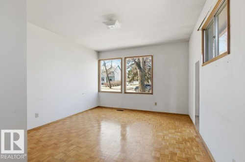 Bright interior space featuring wood-finish parquet flooring, white painted walls, and a white ceiling with a flush-mount light fixture - 10459 66 Avenue Nw, Edmonton, AB - Indoor Photo Showing Other Room