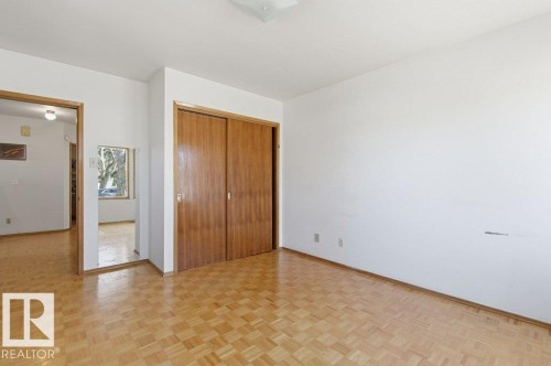 Parquet wood-finish flooring throughout, featuring a spacious room with white walls, wood-finish sliding closet doors, and recessed lighting - 10459 66 Avenue Nw, Edmonton, AB - Indoor Photo Showing Other Room