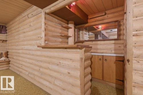 Log cabin style interior paneling throughout, featuring a built-in bar with wood cabinetry and a pass-through window - 10459 66 Avenue Nw, Edmonton, AB - Indoor Photo Showing Other Room