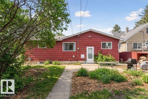 Red exterior siding with white trim around windows and a white entry door - 10459 66 Avenue Nw, Edmonton, AB - Outdoor