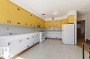 Kitchen featuring extensive upper yellow cabinetry and lower white cabinetry with decorative hardware, white countertops, and white appliances - 10459 66 Avenue Nw, Edmonton, AB  - Indoor Photo Showing Kitchen 