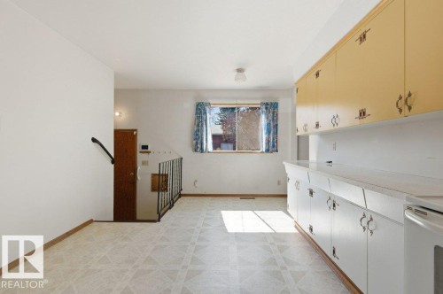 Kitchen and dining area featuring a full wall of cabinetry with both upper and lower storage, white countertops, and patterned linoleum flooring - 10459 66 Avenue Nw, Edmonton, AB - Indoor Photo Showing Other Room