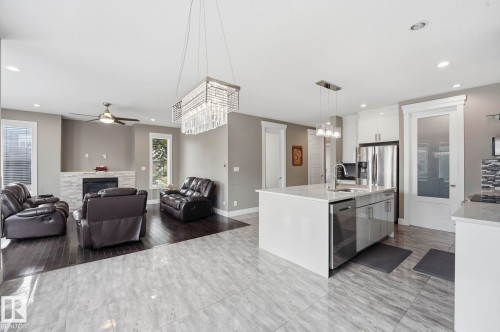 Open-concept living space featuring a central kitchen island with a built-in sink and stainless steel appliances - 1051 174 Street Sw, Edmonton, AB - Indoor