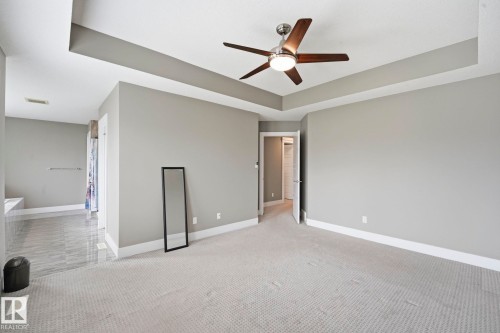 Spacious room featuring a tray ceiling with a ceiling fan, light gray wall paint, and white baseboards - 1051 174 Street Sw, Edmonton, AB - Indoor Photo Showing Other Room