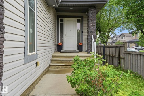 Stone accent pillars flank the entrance, featuring a white door with a clear glass sidelight and transom window - 1051 174 Street Sw, Edmonton, AB - Outdoor