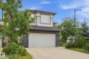 Modern two-story exterior featuring a two-car garage, stone veneer accents, and light-toned siding - 1051 174 Street Sw, Edmonton, AB  - Outdoor 