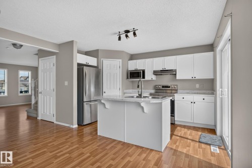 Modern kitchen featuring white cabinetry, stainless steel appliances, a center island with sink, and wood-finish flooring - 8923 173 Avenue Nw, Edmonton, AB - Indoor Photo Showing Kitchen With Stainless Steel Kitchen With Upgraded Kitchen