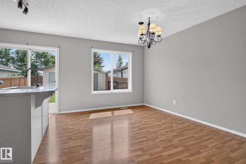 Open-concept room featuring wood-finish flooring, light grey walls, and a multi-arm chandelier - 8923 173 Avenue Nw, Edmonton, AB - Indoor Photo Showing Other Room