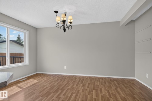 Open-concept space featuring wood-finish flooring, a large window, and a decorative chandelier - 8923 173 Avenue Nw, Edmonton, AB - Indoor Photo Showing Other Room