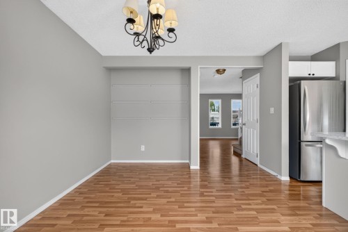 Room featuring wood-finish flooring, a built-in shelving unit, and a black wrought-iron chandelier with fabric shades - 8923 173 Avenue Nw, Edmonton, AB - Indoor