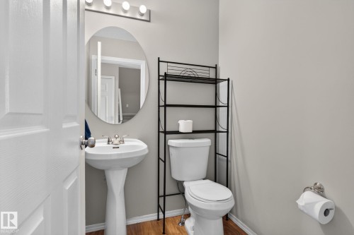 Pedestal sink with chrome faucet, oval mirror, and three-bulb vanity lighting - 8923 173 Avenue Nw, Edmonton, AB - Indoor Photo Showing Bathroom
