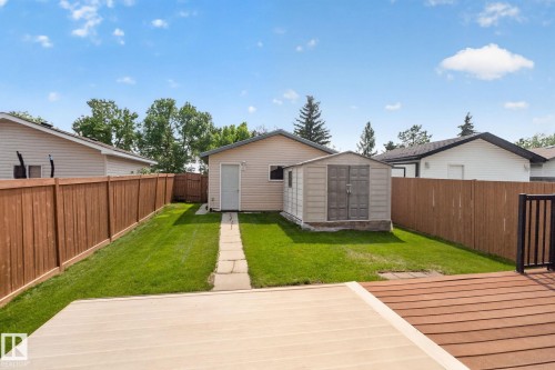 Expansive backyard featuring a manicured lawn, a detached building with siding, a separate storage shed, and a privacy fence - 8923 173 Avenue Nw, Edmonton, AB - Outdoor With Exterior