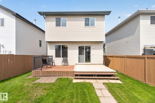 Rear elevation featuring a two-tier wood deck, sliding glass patio door, and a fenced backyard with a stone paver pathway - 8923 173 Avenue Nw, Edmonton, AB - Outdoor With Deck Patio Veranda With Exterior