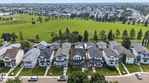 Residential properties featuring pitched roofs and varied architectural styles, bordered by an expansive green space with mature trees - 8923 173 Avenue Nw, Edmonton, AB - Outdoor With View