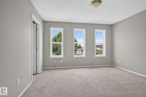 Room with three casement windows, neutral gray wall paint, and gray carpet flooring - 8923 173 Avenue Nw, Edmonton, AB - Indoor Photo Showing Other Room