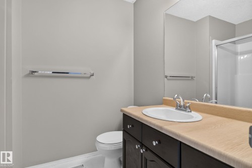 Bathroom featuring a dark wood vanity with a light-toned countertop, an integrated sink, and a chrome faucet - 8923 173 Avenue Nw, Edmonton, AB - Indoor Photo Showing Bathroom