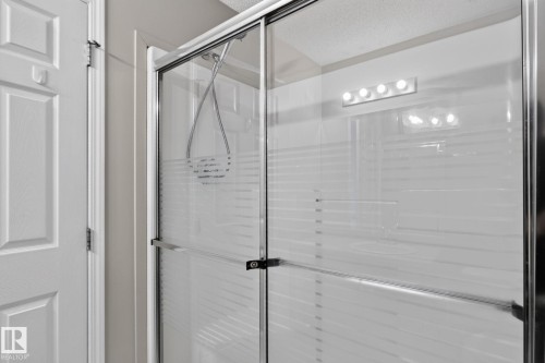 Shower enclosure featuring clear glass panels with frosted accents, a chrome frame, and a mounted shower head - 8923 173 Avenue Nw, Edmonton, AB - Indoor Photo Showing Bathroom