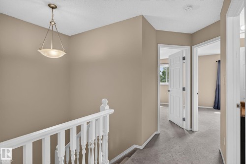 Upper level landing featuring neutral wall paint, white trim, a decorative pendant light fixture, and carpet flooring - 8923 173 Avenue Nw, Edmonton, AB - Indoor Photo Showing Other Room