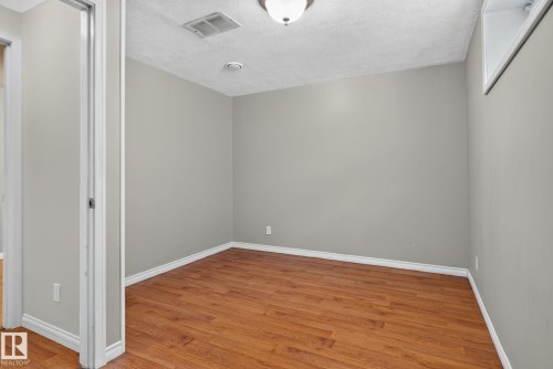 Room with wood-finish flooring, light grey painted walls, white baseboards, and a white ceiling with a flush-mount light fixture - 8923 173 Avenue Nw, Edmonton, AB - Indoor Photo Showing Other Room