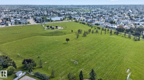 Expansive green space featuring multiple sports fields, mature trees, a paved walking path, and a distant body of water - 8923 173 Avenue Nw, Edmonton, AB - Outdoor With View