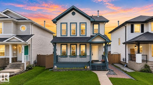 Two-story residence featuring light-colored siding with dark trim, a covered front porch with railings, multiple windows on both levels, and a gabled roofline - 8923 173 Avenue Nw, Edmonton, AB - Outdoor With Deck Patio Veranda With Facade