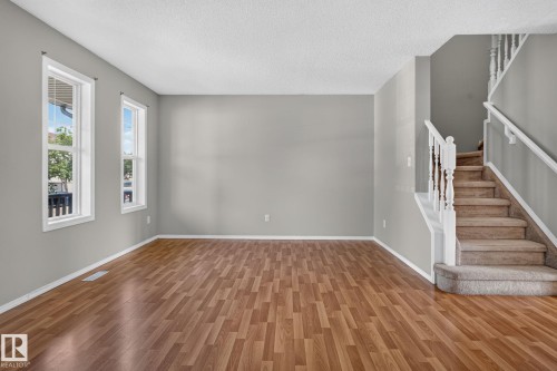 Spacious living area featuring wood-finish flooring, light gray wall paint, and white baseboards - 8923 173 Avenue Nw, Edmonton, AB - Indoor Photo Showing Other Room