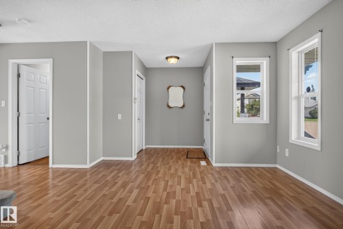 Entryway featuring wood-finish flooring, two windows with white trim, a flush-mount ceiling light fixture, and a white front door - 8923 173 Avenue Nw, Edmonton, AB - Indoor Photo Showing Other Room