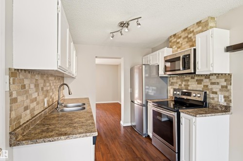 Kitchen featuring white cabinetry, stone-look countertops, stainless steel appliances, and a tiled backsplash - 281 Vantage Lane, Sherwood Park, AB - Indoor Photo Showing Kitchen With Double Sink