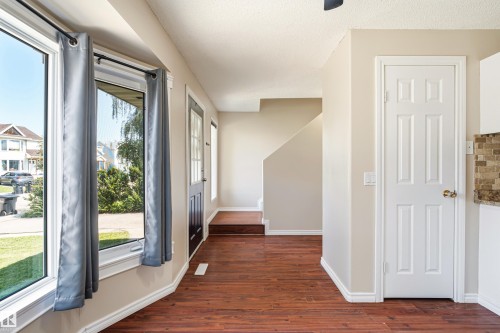 Bay window with white trim, wood-finish flooring, staircase, panel doors, and neutral wall tones - 281 Vantage Lane, Sherwood Park, AB - Indoor Photo Showing Other Room