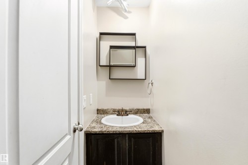 Powder room featuring a single vanity with a granite-look countertop and dark wood-finish cabinetry - 281 Vantage Lane, Sherwood Park, AB - Indoor Photo Showing Bathroom