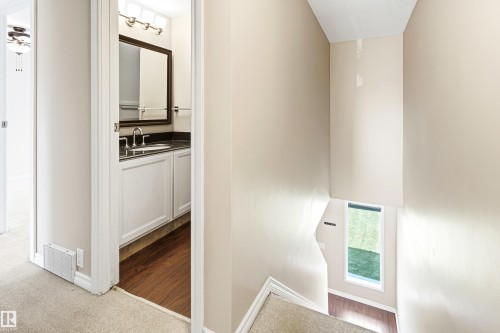 Bathroom featuring a white vanity with dark countertop, wood-finish flooring, and wall-mounted light fixture - 281 Vantage Lane, Sherwood Park, AB - Indoor Photo Showing Other Room