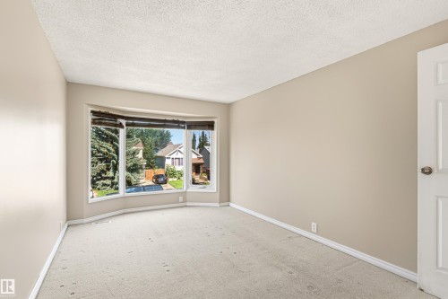 Spacious room featuring a large bay window, neutral paint, baseboard trim, and light-toned carpet - 281 Vantage Lane, Sherwood Park, AB - Indoor Photo Showing Other Room