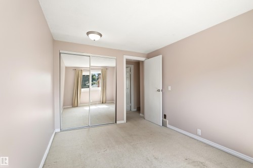 Carpeted room featuring a ceiling-mounted light fixture, mirrored sliding closet doors, a white interior door, and white baseboards - 281 Vantage Lane, Sherwood Park, AB - Indoor Photo Showing Other Room
