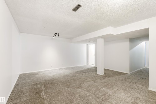 Spacious interior room featuring light-toned carpeting, white painted walls, a textured white ceiling, and track lighting - 281 Vantage Lane, Sherwood Park, AB - Indoor Photo Showing Other Room
