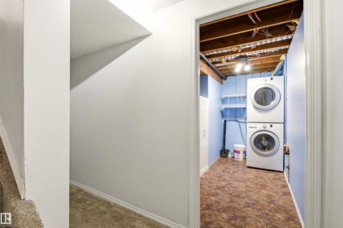 Dedicated laundry area featuring a stacked washer and dryer, exposed ceiling joists, and light blue walls - 281 Vantage Lane, Sherwood Park, AB - Indoor Photo Showing Laundry Room