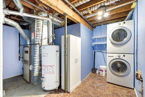Dedicated laundry area featuring a stacked washer and dryer unit, wall-mounted shelving, and a nearby storage cabinet - 281 Vantage Lane, Sherwood Park, AB - Indoor Photo Showing Laundry Room