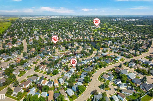 Aerial depiction of a residential subdivision featuring curvilinear streets, varied housing styles, mature trees, and a central pond - 281 Vantage Lane, Sherwood Park, AB - Outdoor With View