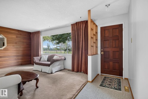Warm wood-paneled accent wall in a living area featuring a large picture window, offering views of the outdoors - 6012 145 Avenue Nw, Edmonton, AB - Indoor