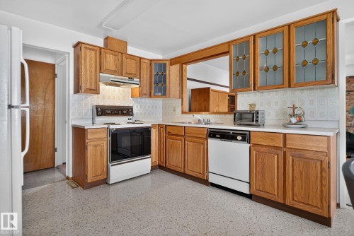 Kitchen featuring wood cabinetry, white countertops, built-in wall oven, and a double basin sink - 6012 145 Avenue Nw, Edmonton, AB - Indoor Photo Showing Kitchen With Double Sink