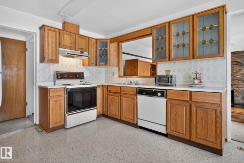 U-shaped kitchen featuring wood cabinetry, white countertops, textured white backsplash, and a built-in oven with overhead range hood - 6012 145 Avenue Nw, Edmonton, AB - Indoor Photo Showing Kitchen With Double Sink