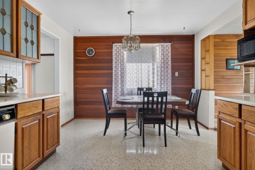 Dining area featuring a wood plank accent wall, a central chandelier, and light-colored flooring - 6012 145 Avenue Nw, Edmonton, AB - Indoor Photo Showing Dining Room