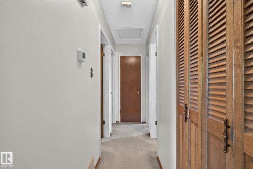 Hallway featuring a neutral color palette, wood louvered doors, and carpet flooring - 6012 145 Avenue Nw, Edmonton, AB - Indoor Photo Showing Other Room