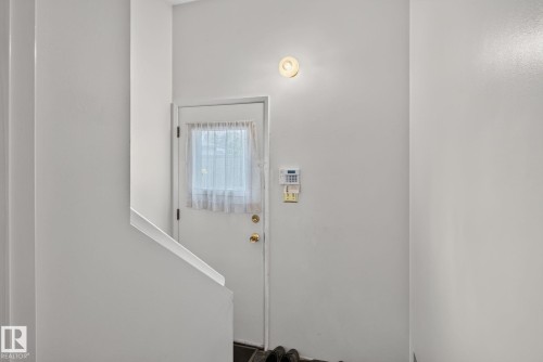 White interior door with a paneled window and brass-finish hardware - 6012 145 Avenue Nw, Edmonton, AB - Indoor Photo Showing Other Room