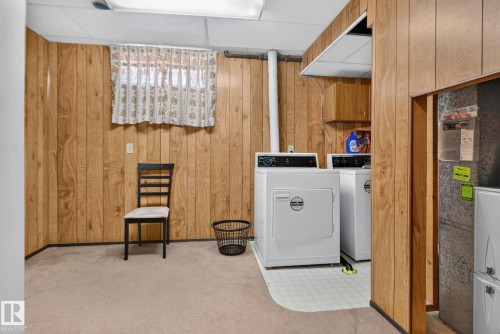 Utility area featuring wood paneling, drop ceiling, and carpeted flooring - 6012 145 Avenue Nw, Edmonton, AB - Indoor Photo Showing Laundry Room