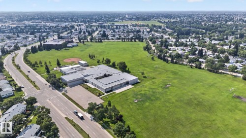 Expansive green spaces featuring a baseball diamond, multiple soccer goals, mature trees, and a visible school building - 6012 145 Avenue Nw, Edmonton, AB - Outdoor With View